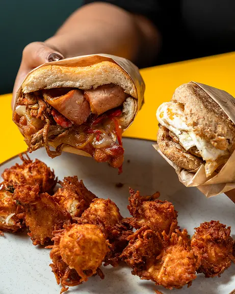 Hands holding two breakfast sandwiches over hashbrown tumblers Hands holding two breakfast sandwiches over hashbrown tumblers